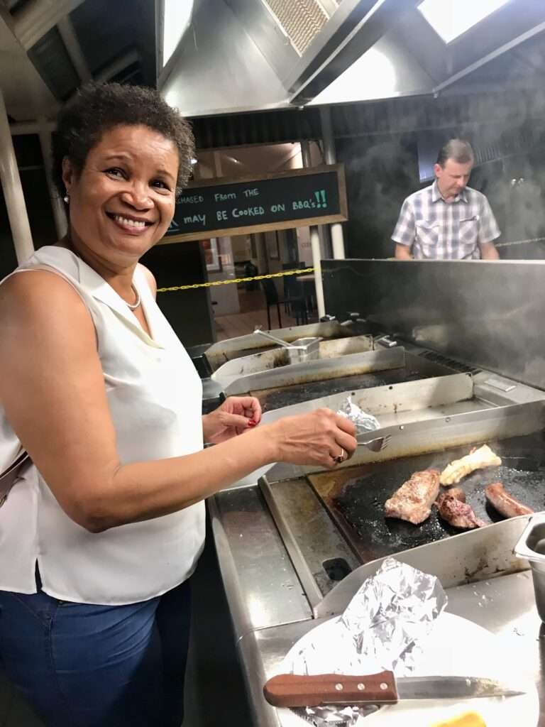 Molly from Mollywozhere travel blog barbecuing crocodile tail, emu sausage and kangaroo steak to eat in Australian Red Centre.