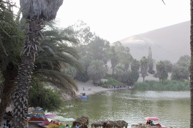 Molly from Mollywozhere travel blog showing Huacachina, an oasis surrounded by enormous sand dunes, Peru.