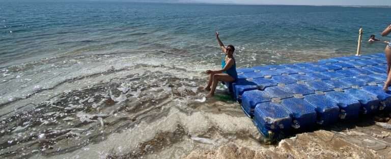 Molly from Mollywozhere travel sitting on blue rafts floating in the Dead Sea, Jordan.