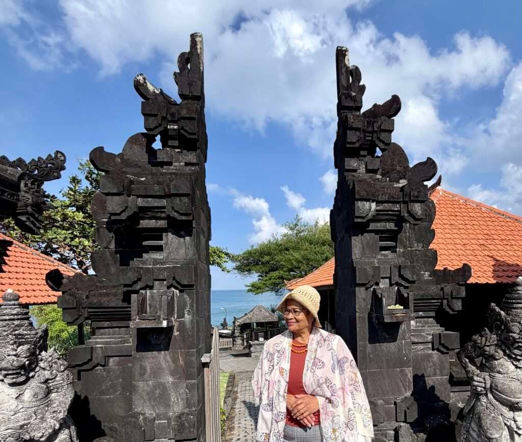 Molly of Mollywozhere standing in front the gates of a temple in Tanah Lot, Bali, Indonesia.