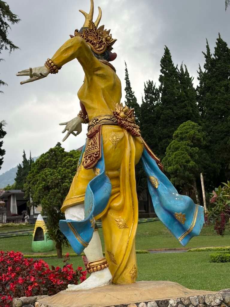 Molly from Mollywozhere looking at the statue of a dancer dressed in gold and blue traditional dress in Ulun Danu Beratan Temple,Bali.