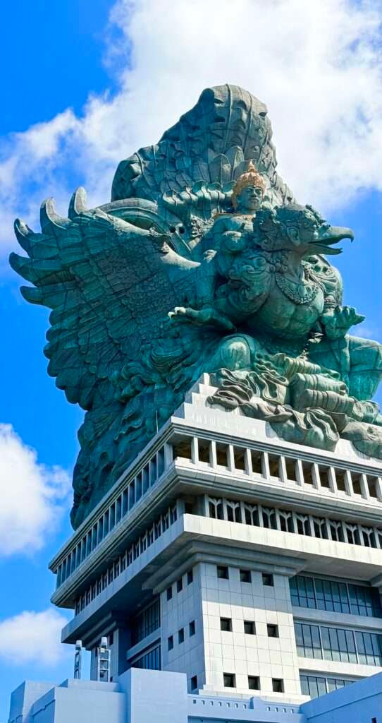 Molly from Mollywozhere travel blog looking at the colossus Garuda Wisnu Kencana (GWK) in the clouds with an illusion of flying, Bali.