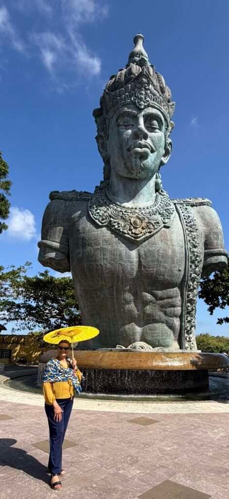 Molly from Mollywozhere travel blog looking at a massive sculpted stone head at the top of GWK Cultural Park, Bali.