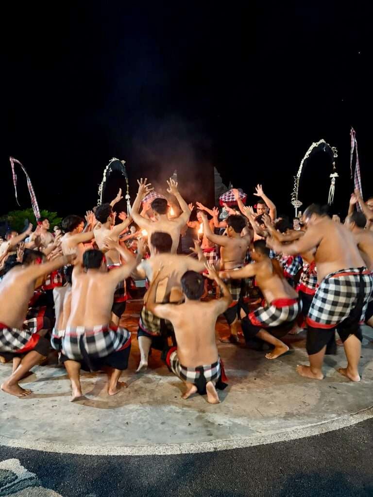 Molly from Mollywozhere travel blog in the audience watching male chorus in a circle chanting cak-cak-cak at the Kecat Dance & Fire Show, at Uluwatu Temple, Bali.