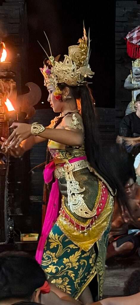 Molly from Mollywozhere travel blog watching a woman dressed in traditional Balinese dress dancing at Kecat Dance & Fire show in Uluwatu, Bali.