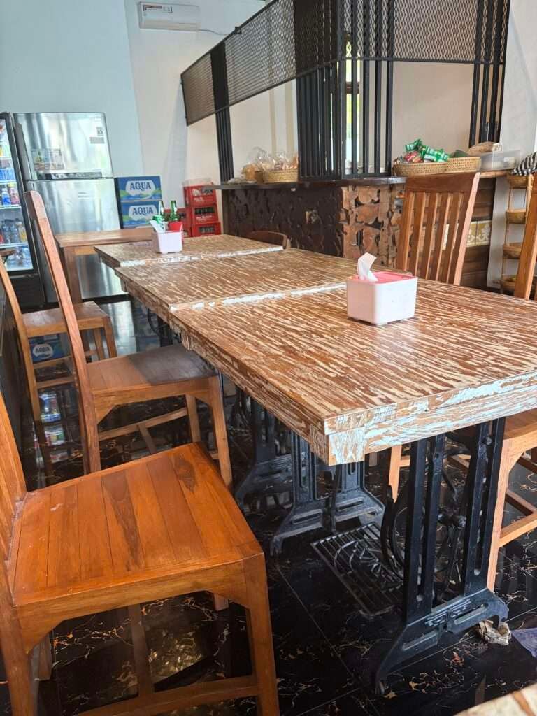 Molly from Mollywozhere travel blog showing a close up of a restaurant table recycled from a vintage Singer sewing machine with iron foot pedals in a Balinese warung.