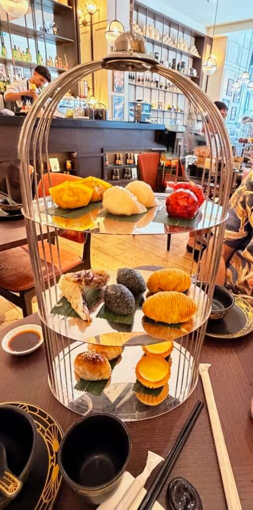 Molly from Mollywozhere travel blog showing a 3 tier afternoon tea with a twist, flaky pastry, dim sum and classic tart at the Dim Sum Library, London.